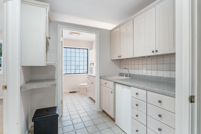 kitchen with white cabinets, tasteful backsplash, white dishwasher, and sink