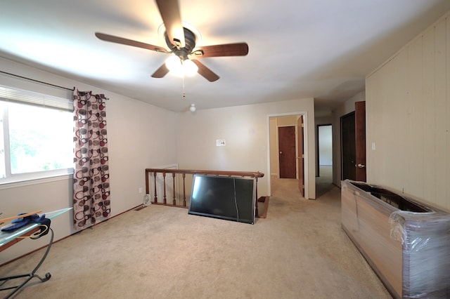 unfurnished room with light carpet, ceiling fan, and wood walls