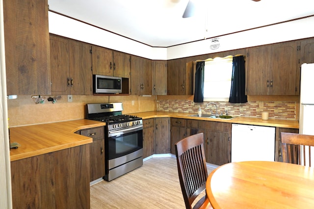 kitchen featuring ceiling fan, sink, tasteful backsplash, appliances with stainless steel finishes, and light wood-type flooring