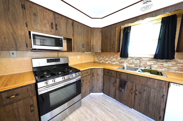 kitchen with decorative backsplash, sink, appliances with stainless steel finishes, and light hardwood / wood-style flooring