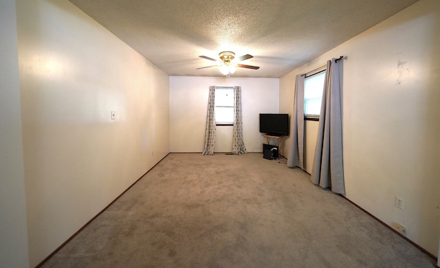 empty room with ceiling fan, light colored carpet, and a textured ceiling