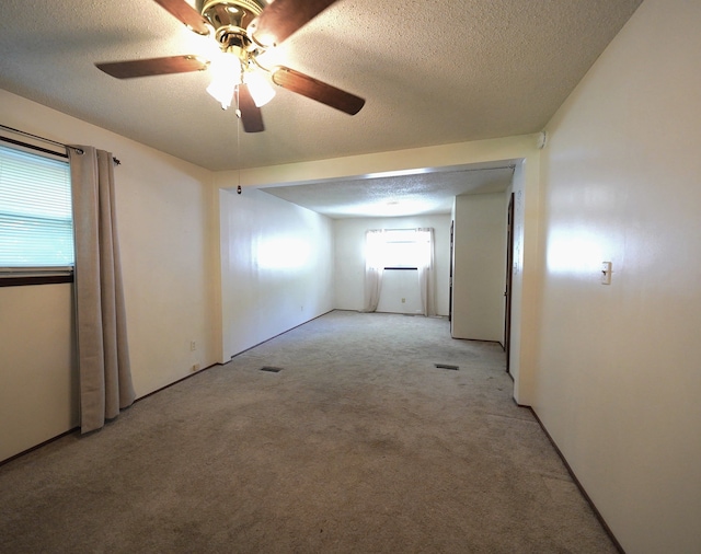 carpeted spare room featuring ceiling fan and a textured ceiling