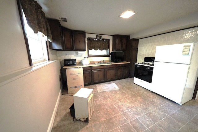 kitchen featuring dark brown cabinets, white appliances, sink, and tasteful backsplash