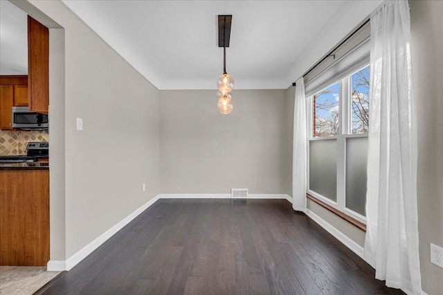 unfurnished dining area with dark wood-type flooring