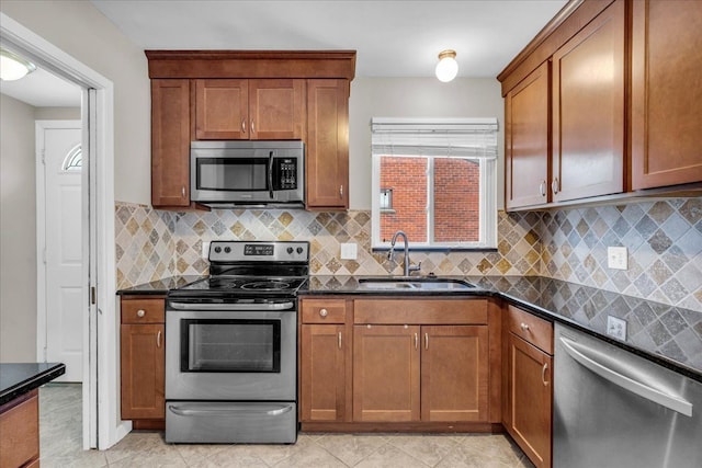 kitchen with appliances with stainless steel finishes, sink, and dark stone countertops