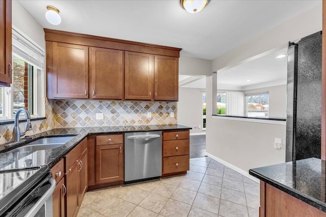 kitchen with dark stone countertops, stainless steel dishwasher, decorative backsplash, sink, and light tile patterned floors