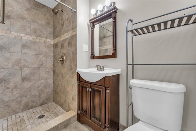 bathroom with toilet, vanity, and a tile shower