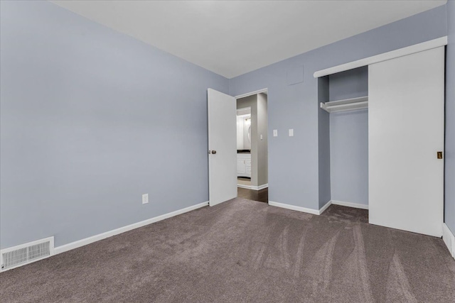 unfurnished bedroom with dark carpet and a closet