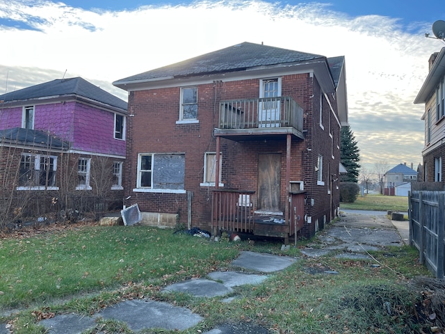 rear view of house featuring a yard and a balcony