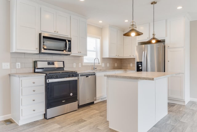 kitchen featuring a center island, stainless steel appliances, white cabinetry, and light hardwood / wood-style flooring