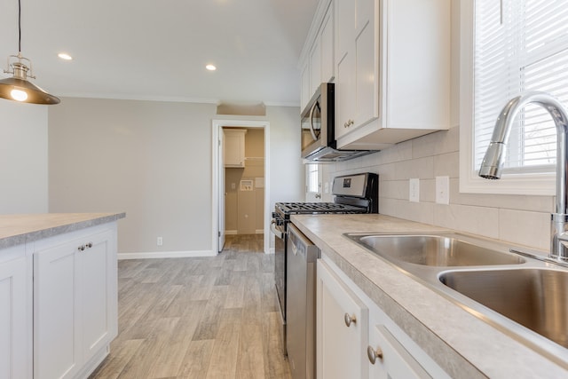 kitchen featuring sink, appliances with stainless steel finishes, decorative light fixtures, white cabinets, and ornamental molding