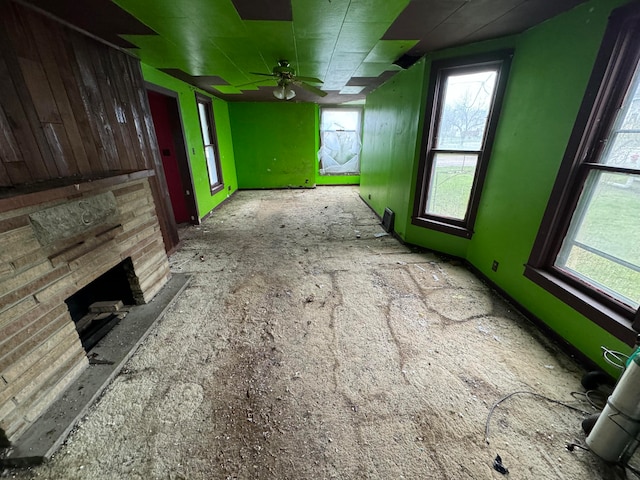 unfurnished living room with ceiling fan and a stone fireplace