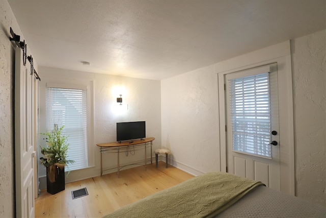 bedroom featuring a barn door and light wood-type flooring