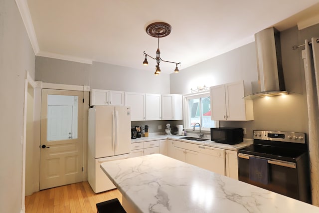 kitchen with sink, hanging light fixtures, wall chimney range hood, white appliances, and light wood-type flooring