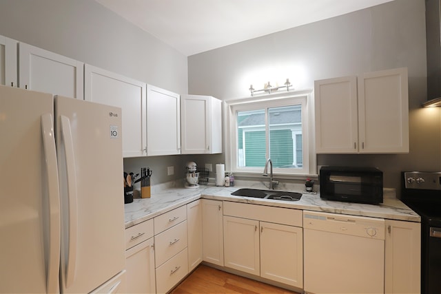 kitchen with light stone countertops, light wood-type flooring, white appliances, sink, and white cabinets