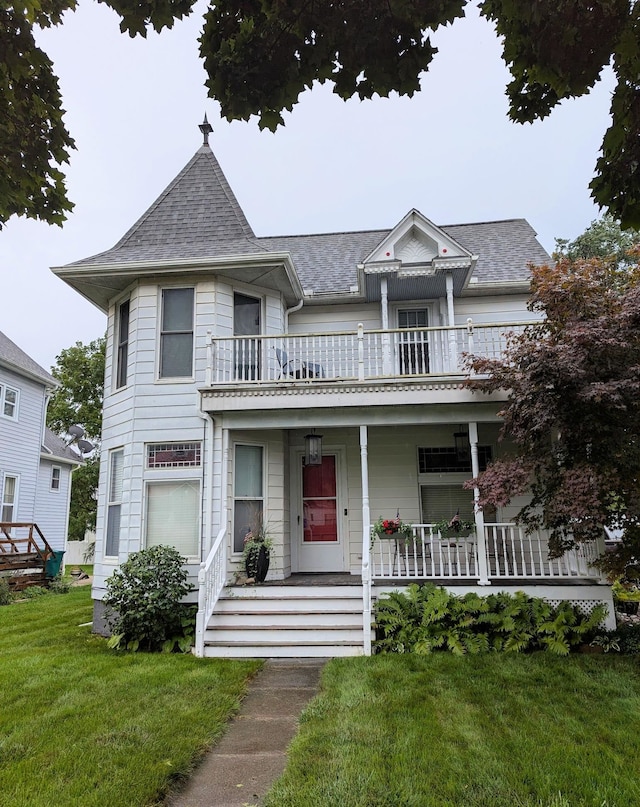 victorian house featuring a porch, a balcony, and a front lawn