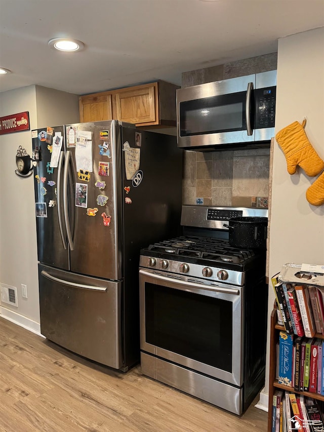 kitchen with decorative backsplash, appliances with stainless steel finishes, and light wood-type flooring