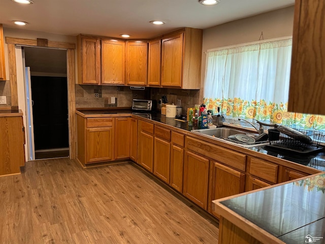 kitchen featuring decorative backsplash, sink, and light wood-type flooring