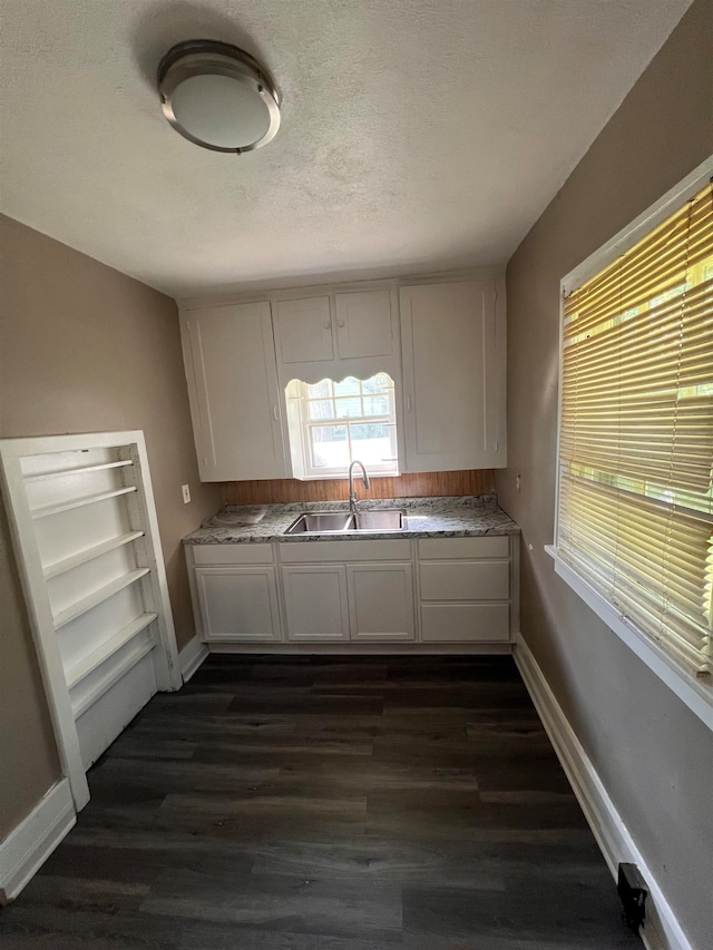 kitchen with white cabinets, a textured ceiling, sink, and dark wood-type flooring