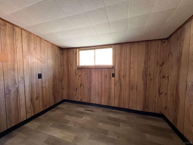 unfurnished room featuring wooden walls and dark hardwood / wood-style floors