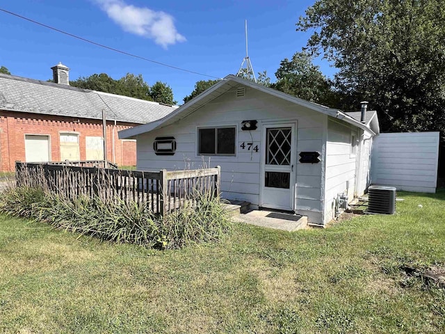 rear view of house featuring a lawn and cooling unit