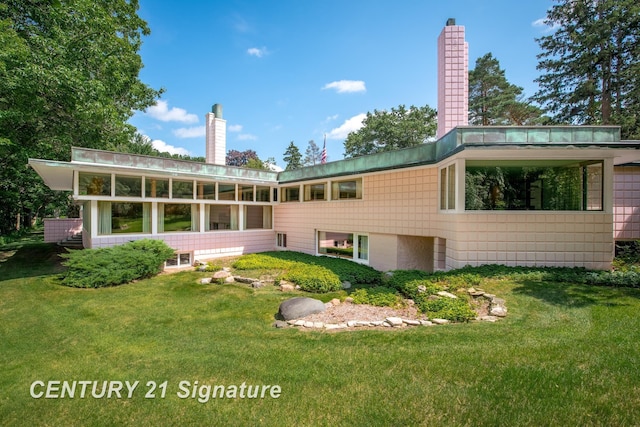 rear view of property featuring a lawn, a chimney, and a sunroom