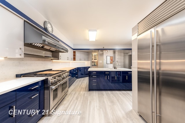 kitchen with high quality appliances, light wood-type flooring, exhaust hood, blue cabinets, and open shelves