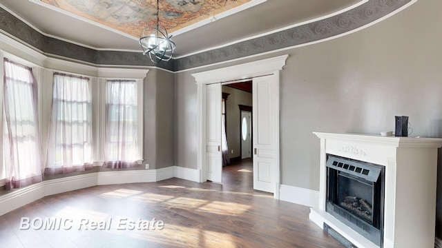 unfurnished dining area featuring hardwood / wood-style floors, a notable chandelier, a raised ceiling, and crown molding