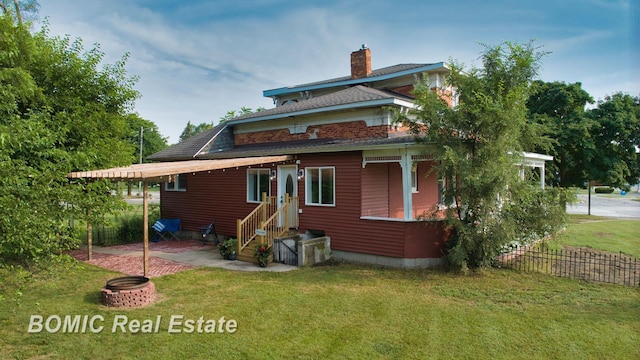 back of house featuring an outdoor fire pit, a patio area, and a lawn