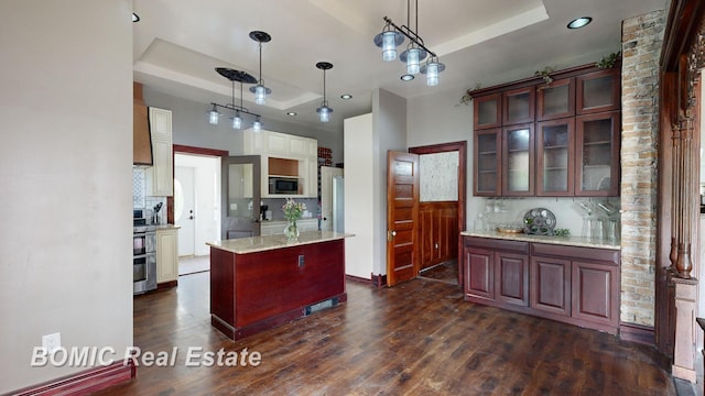 kitchen featuring dark wood-type flooring, stainless steel appliances, a raised ceiling, pendant lighting, and decorative backsplash