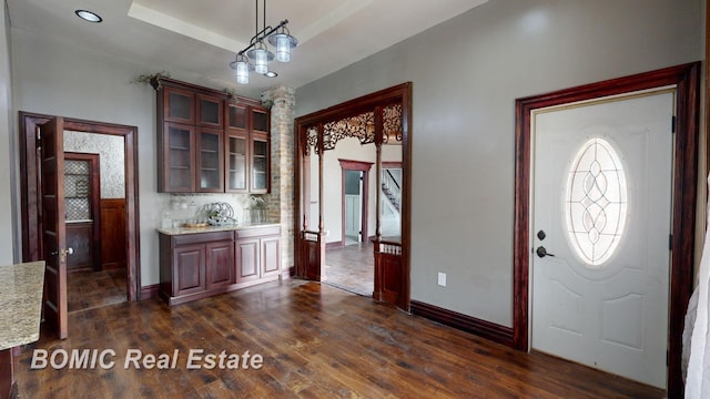 entryway featuring a tray ceiling, dark wood-type flooring, and a notable chandelier