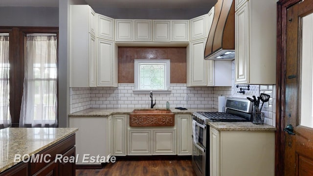 kitchen with light stone countertops, dark hardwood / wood-style flooring, premium range hood, sink, and stainless steel gas stove