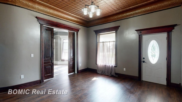 entrance foyer with a chandelier, crown molding, and dark wood-type flooring