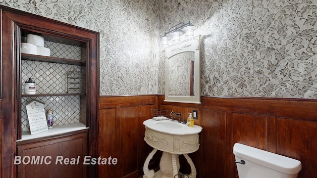 bathroom with toilet and wooden walls