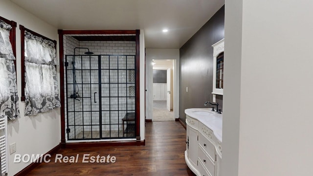 bathroom with tiled shower, vanity, and hardwood / wood-style flooring