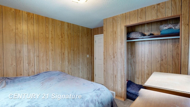 bedroom with wooden walls, a closet, carpet, and a textured ceiling