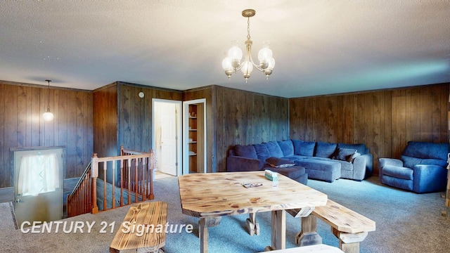 dining space featuring carpet flooring, wooden walls, a textured ceiling, and a notable chandelier