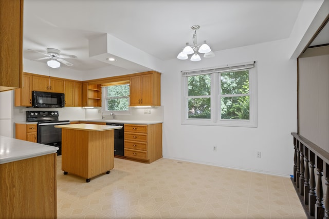 kitchen featuring ceiling fan with notable chandelier, a center island, hanging light fixtures, and black appliances