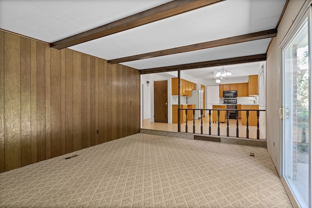 unfurnished room featuring beam ceiling, wood walls, a chandelier, and light carpet