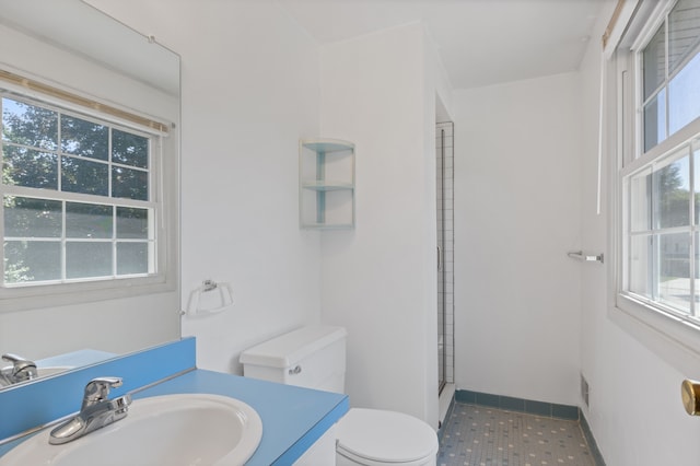 bathroom with an enclosed shower, vanity, toilet, and tile patterned flooring