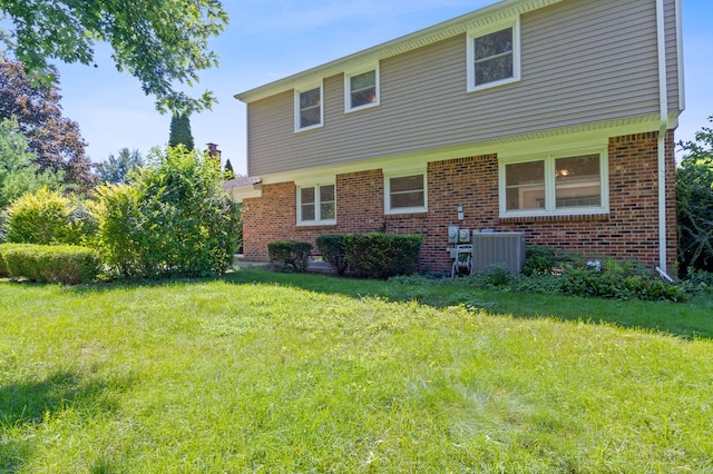 rear view of property with central AC and a yard