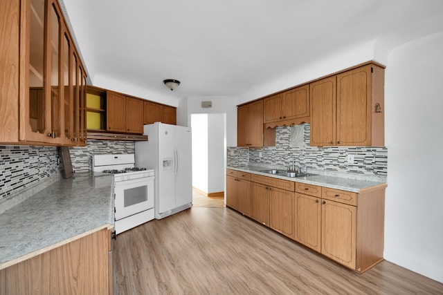 kitchen with backsplash, light hardwood / wood-style flooring, white appliances, and sink