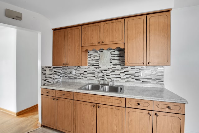 kitchen with tasteful backsplash, light hardwood / wood-style flooring, and sink