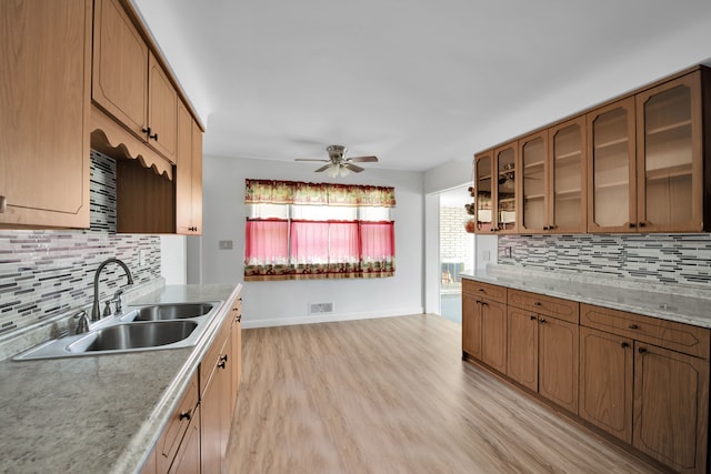 kitchen featuring tasteful backsplash, light hardwood / wood-style flooring, ceiling fan, and sink