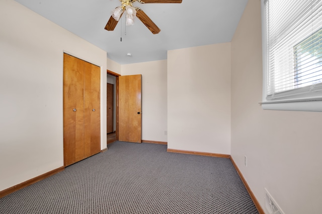 unfurnished bedroom featuring ceiling fan, a closet, and dark carpet