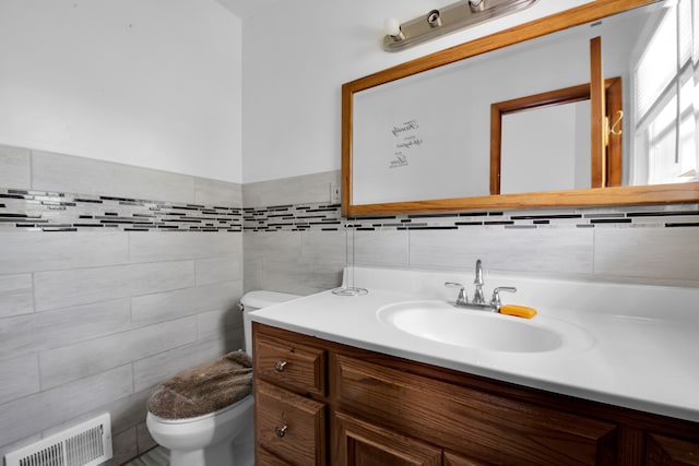 bathroom featuring vanity, toilet, and tile walls