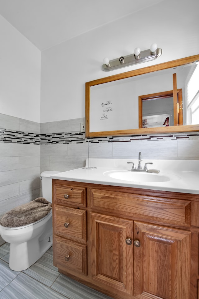 bathroom with tile patterned flooring, vanity, toilet, and tile walls