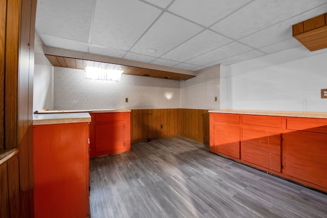 interior space featuring light wood-type flooring, a drop ceiling, and wooden walls