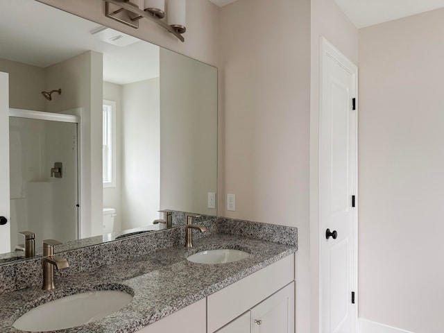 bathroom featuring vanity, a shower with door, and toilet