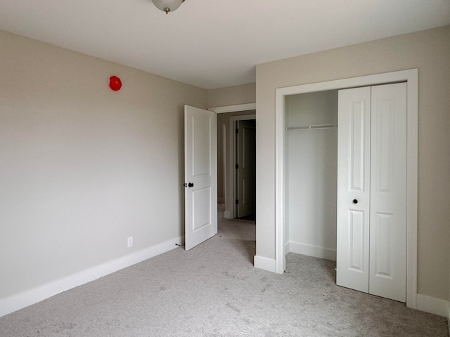 unfurnished bedroom featuring a closet and light carpet